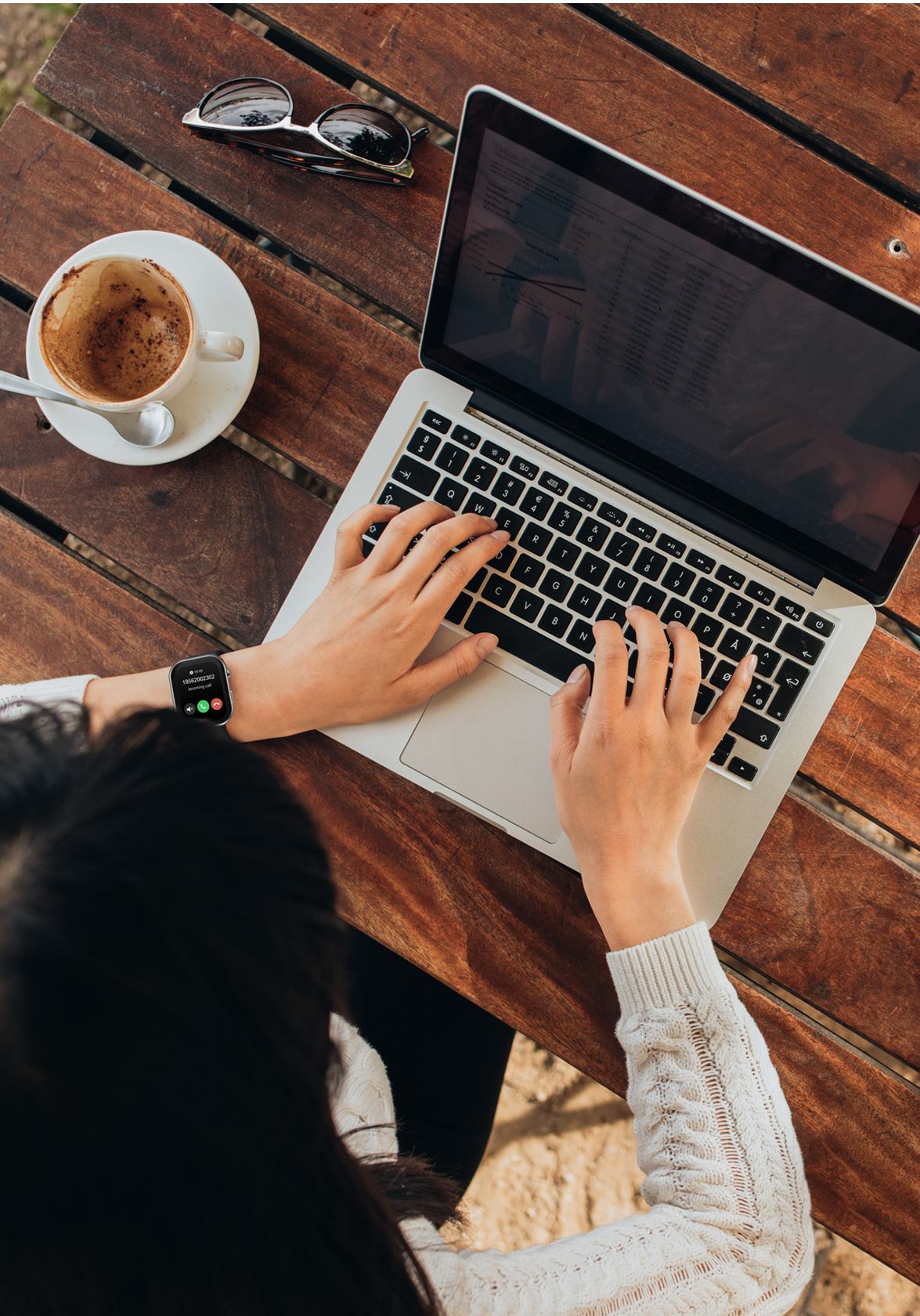 Person using a laptop on a wooden table with a cup of coffee and sunglasses wearing air 5 pro