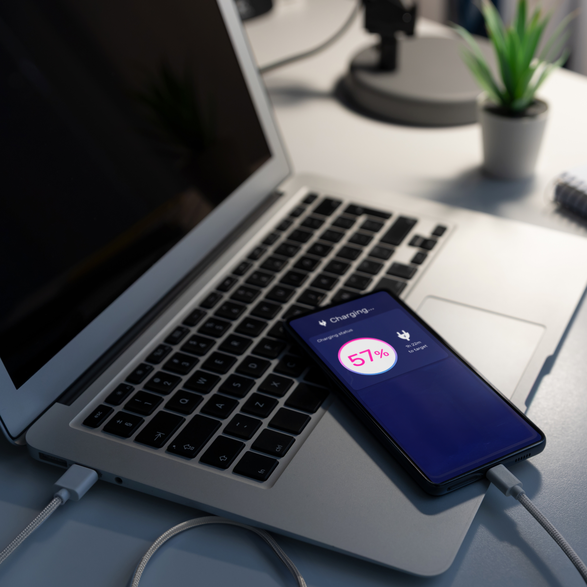 Smartphone charging on a laptop with a visible battery percentage display
