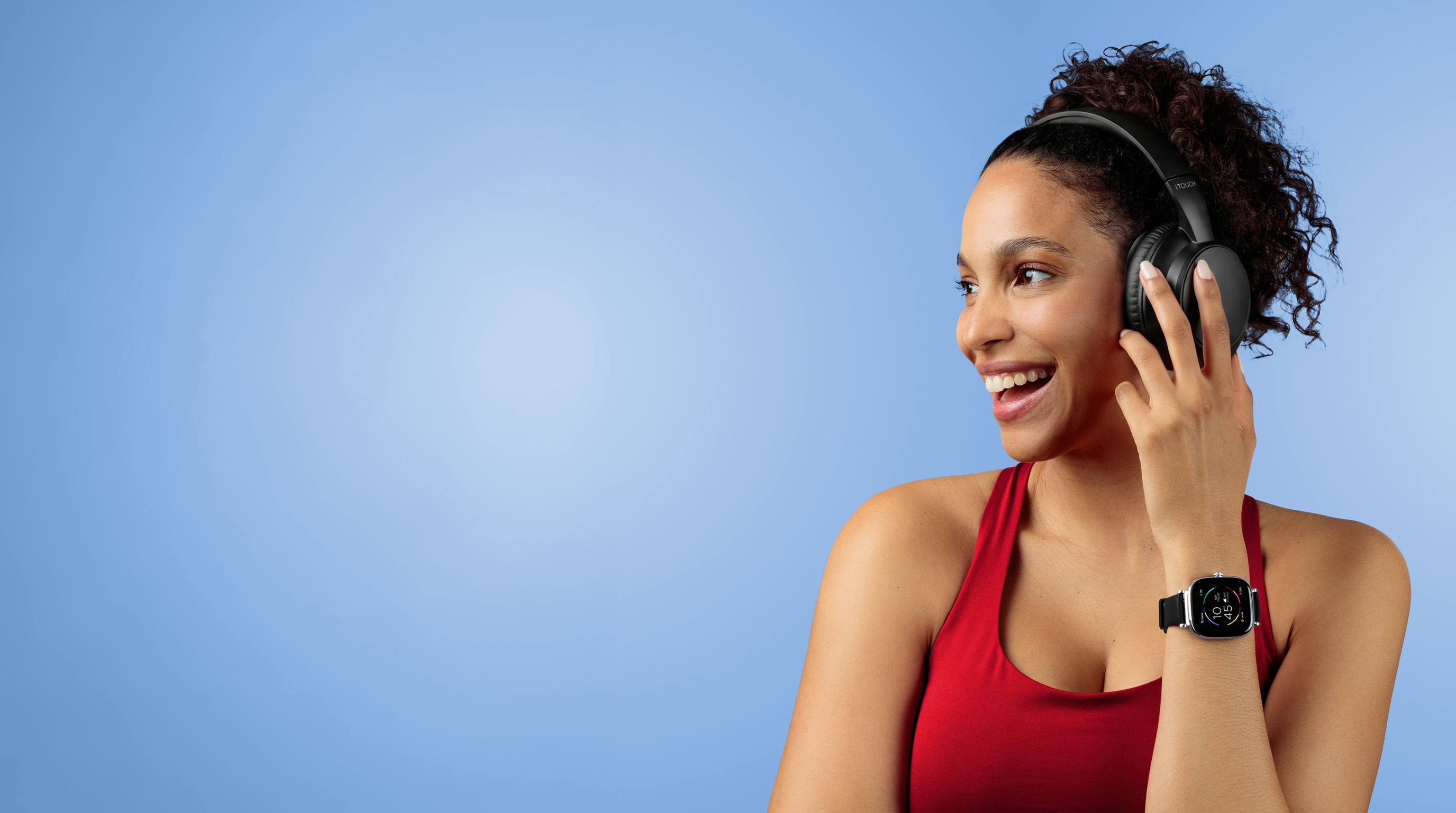 Woman wearing headphones and a smartwatch, smiling against a blue background